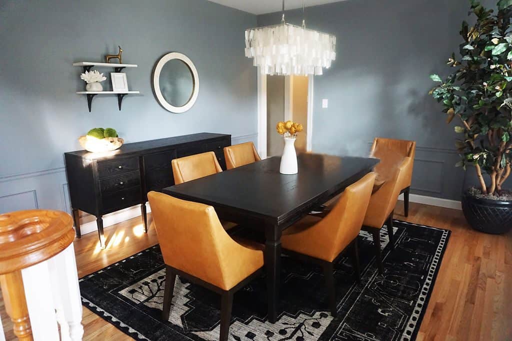 dining room with black wood table, orange/yellow dining chairs, 6 total, area rug, glass light fixture and blue accented walls