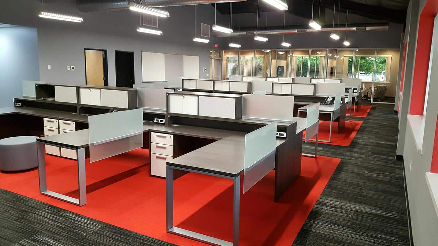 Modern open office desk layout, silver, red, dark wood colors. Sleek, minimal design and layout.